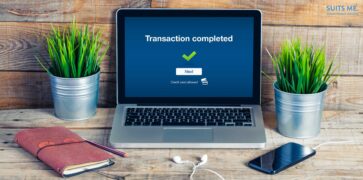 Transaction completed notification in a laptop screen. Wooden office desk with business stuff. Faster Payments Concept