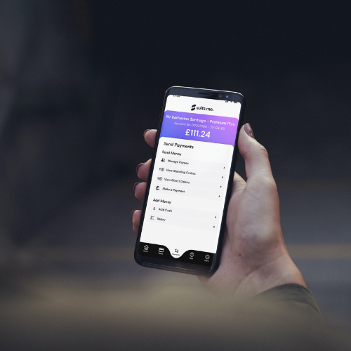 lack background with person holding mobile phone using the Suits Me® mobile banking app